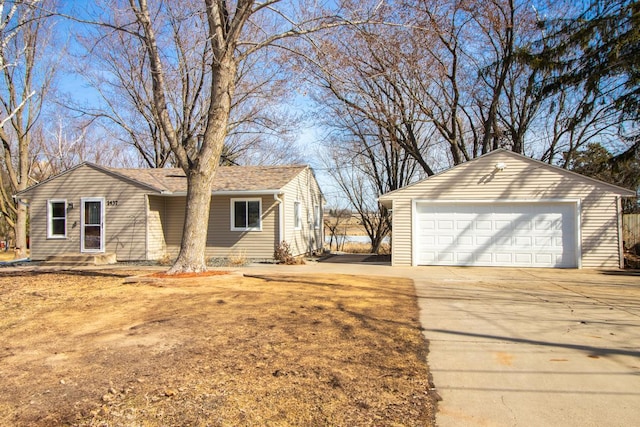 view of side of property with an outbuilding, a shingled roof, and a detached garage