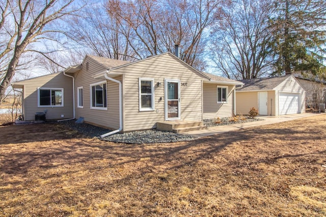 back of property with an outbuilding, a detached garage, and central AC