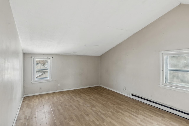 interior space with a baseboard heating unit, light wood-type flooring, lofted ceiling, and baseboards