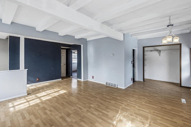 spare room featuring an inviting chandelier, baseboards, visible vents, and wood finished floors