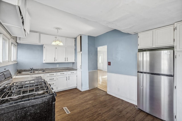 kitchen featuring black range with gas cooktop, decorative light fixtures, freestanding refrigerator, white cabinetry, and a sink