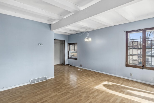 spare room featuring visible vents, a notable chandelier, baseboards, and wood finished floors