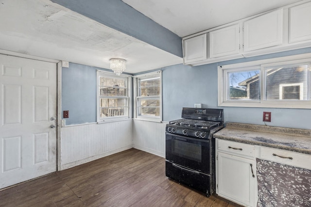 kitchen featuring white cabinets, dark wood finished floors, dark countertops, a wainscoted wall, and black gas stove