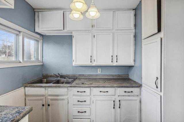 kitchen featuring dark countertops, a sink, and white cabinets