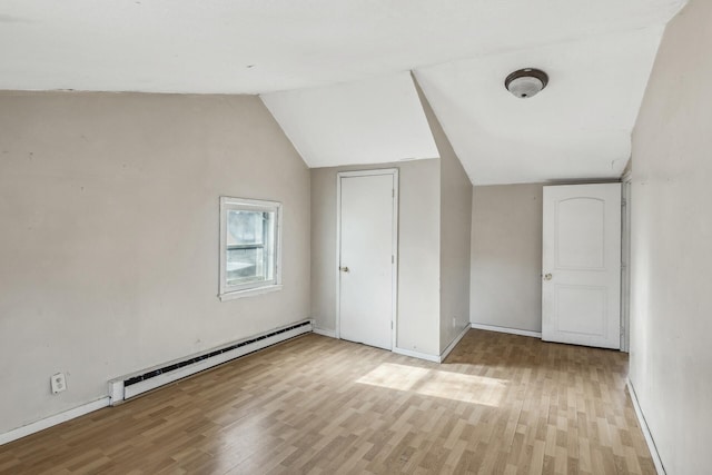 bonus room featuring a baseboard heating unit, baseboards, lofted ceiling, and light wood-style floors