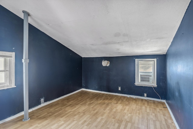 additional living space featuring light wood-type flooring, cooling unit, lofted ceiling, and baseboards