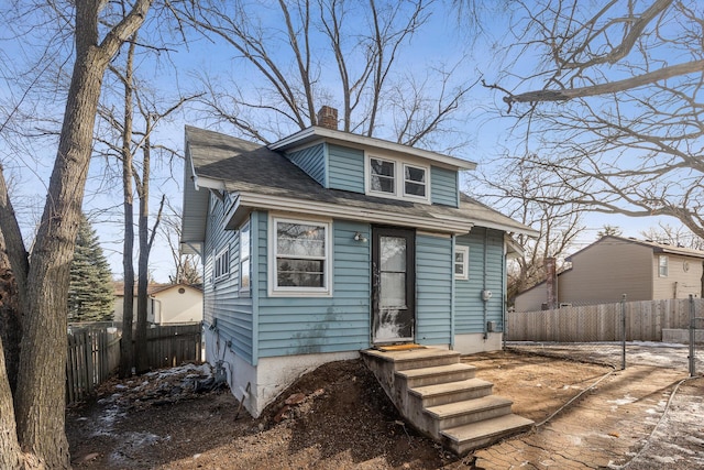 bungalow-style home featuring fence and a chimney