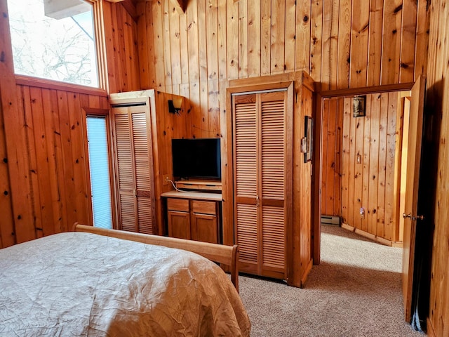 bedroom with wooden walls, carpet floors, and a baseboard heating unit