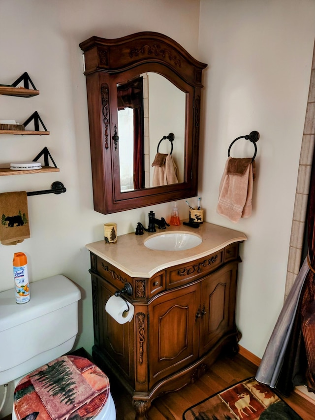 bathroom featuring toilet, vanity, and wood finished floors