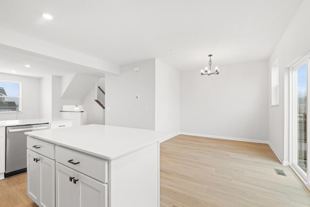 kitchen with white cabinetry, hanging light fixtures, a center island, light hardwood / wood-style floors, and stainless steel dishwasher