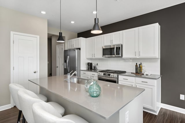 kitchen featuring an island with sink, appliances with stainless steel finishes, a breakfast bar area, and pendant lighting