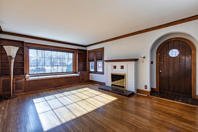 unfurnished living room featuring a brick fireplace, crown molding, and dark hardwood / wood-style floors