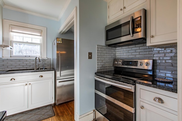 kitchen featuring appliances with stainless steel finishes, tasteful backsplash, ornamental molding, white cabinets, and dark hardwood / wood-style flooring