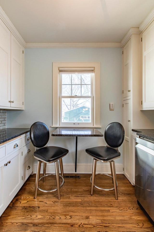 dining space with crown molding and dark wood-type flooring