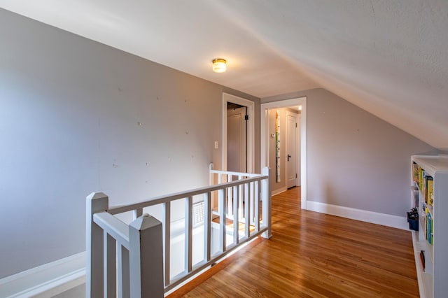 corridor with lofted ceiling and hardwood / wood-style floors