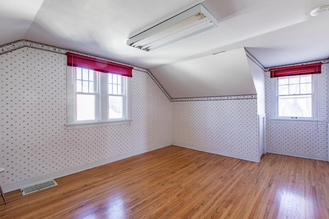 additional living space featuring hardwood / wood-style flooring and vaulted ceiling