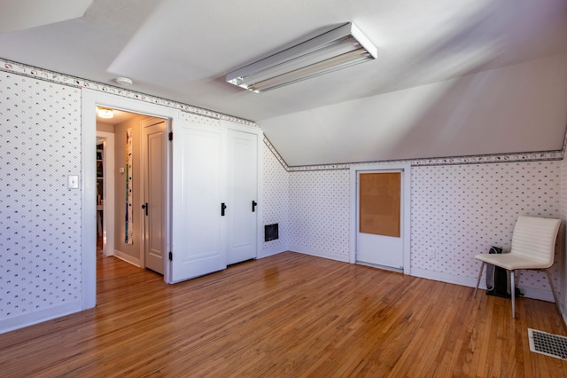 additional living space featuring wood-type flooring and vaulted ceiling