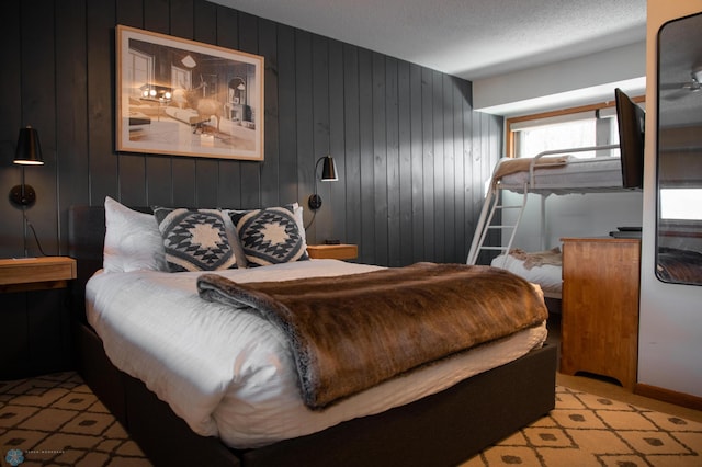 bedroom featuring light colored carpet, a textured ceiling, and wood walls