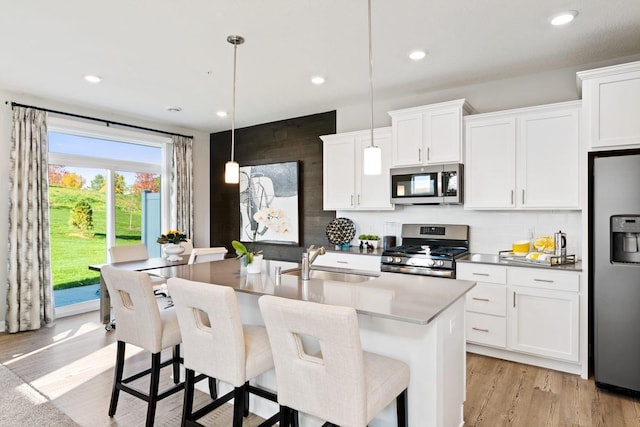 kitchen with hanging light fixtures, white cabinetry, appliances with stainless steel finishes, and sink