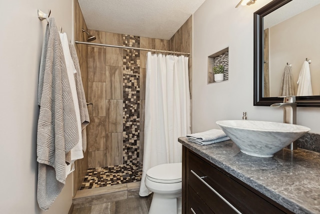 bathroom with a shower with shower curtain, vanity, toilet, and a textured ceiling