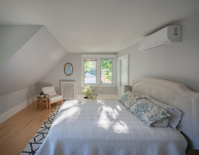 bedroom featuring vaulted ceiling, radiator heating unit, wood-type flooring, and a wall unit AC