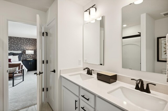 ensuite bathroom featuring a sink, double vanity, connected bathroom, and wallpapered walls