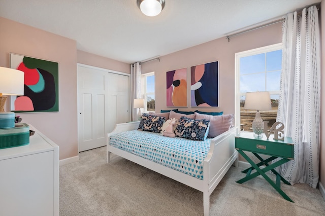 bedroom featuring baseboards, a closet, and light colored carpet