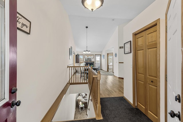 hall featuring dark carpet and vaulted ceiling