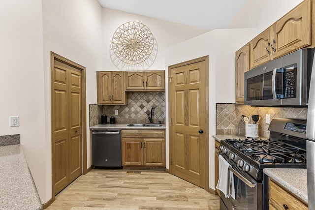 kitchen with lofted ceiling, sink, stainless steel appliances, light hardwood / wood-style floors, and decorative backsplash