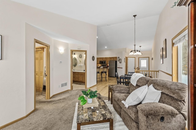 living room featuring light colored carpet, lofted ceiling, and a chandelier