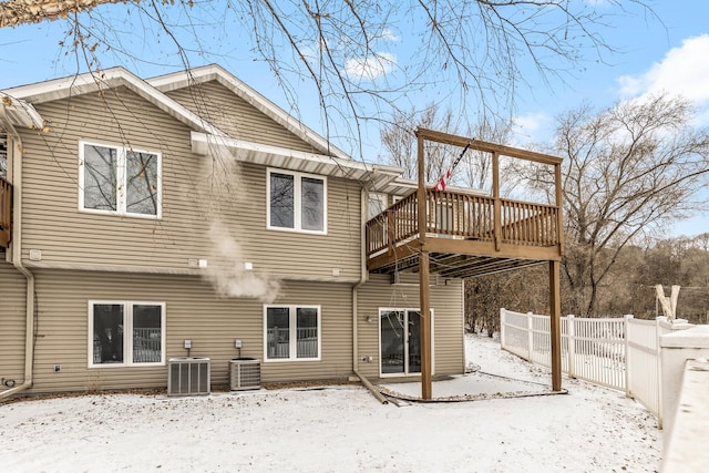 snow covered house featuring central AC and a deck