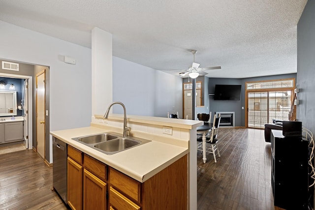 kitchen featuring sink, a textured ceiling, stainless steel dishwasher, dark hardwood / wood-style floors, and a kitchen island with sink