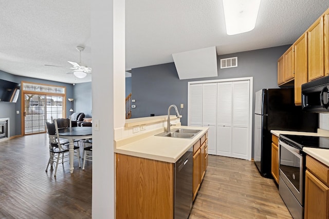 kitchen featuring stainless steel electric stove, dishwashing machine, sink, and light wood-type flooring