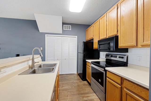 kitchen featuring sink, tasteful backsplash, stainless steel electric range, a textured ceiling, and light hardwood / wood-style floors