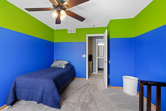 carpeted bedroom featuring ceiling fan and a textured ceiling