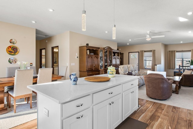 kitchen featuring a kitchen island, light wood-type flooring, white cabinetry, and decorative light fixtures