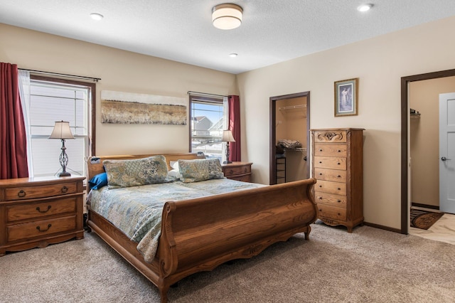 carpeted bedroom featuring a closet, a walk in closet, and a textured ceiling