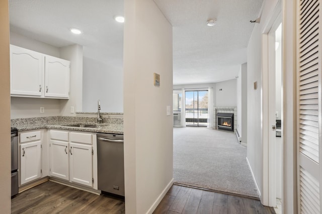 kitchen featuring stainless steel dishwasher, a glass covered fireplace, range, and white cabinets