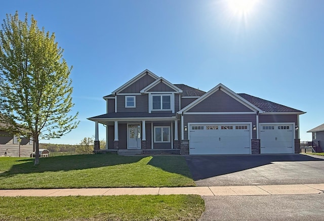 29332 Scenic Dr, Chisago City, MN 55013 - craftsman-style home featuring a garage, asphalt driveway, a front lawn, covered porch, and stone siding
