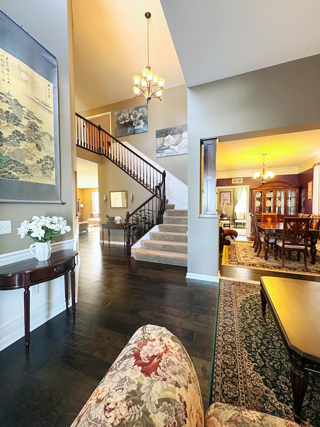 foyer entrance featuring baseboards, a towering ceiling, dark wood-style floors, stairs, and a chandelier