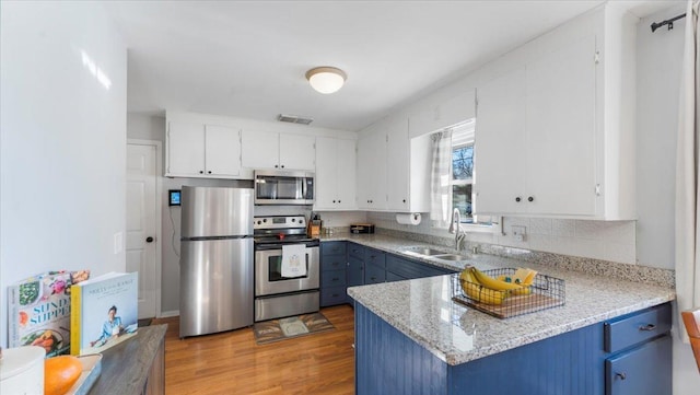 kitchen featuring white cabinetry, stainless steel appliances, and blue cabinets