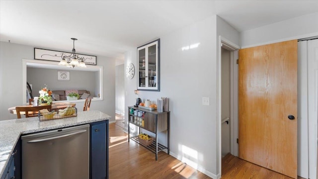 kitchen with dishwasher, light stone counters, light hardwood / wood-style floors, blue cabinets, and decorative light fixtures