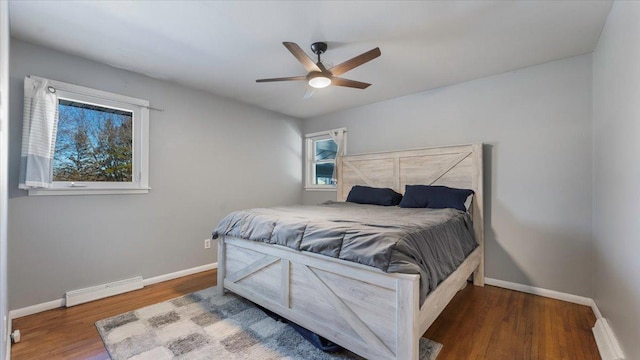 bedroom featuring ceiling fan, dark hardwood / wood-style flooring, and a baseboard heating unit