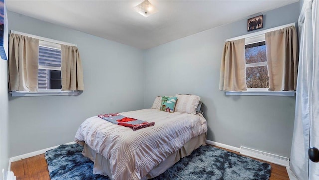 bedroom with hardwood / wood-style floors and baseboard heating