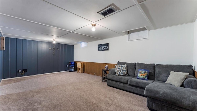 carpeted living room with wood walls