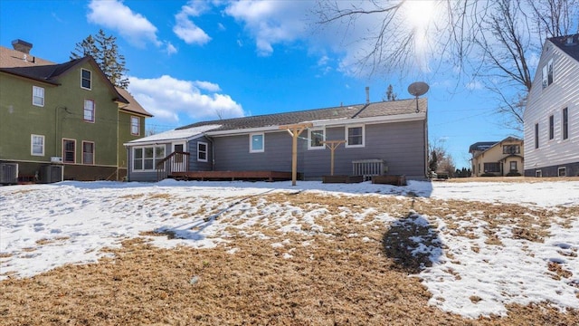 snow covered rear of property featuring a sunroom and central AC unit