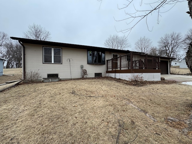 back of house with a wooden deck, a garage, and a lawn