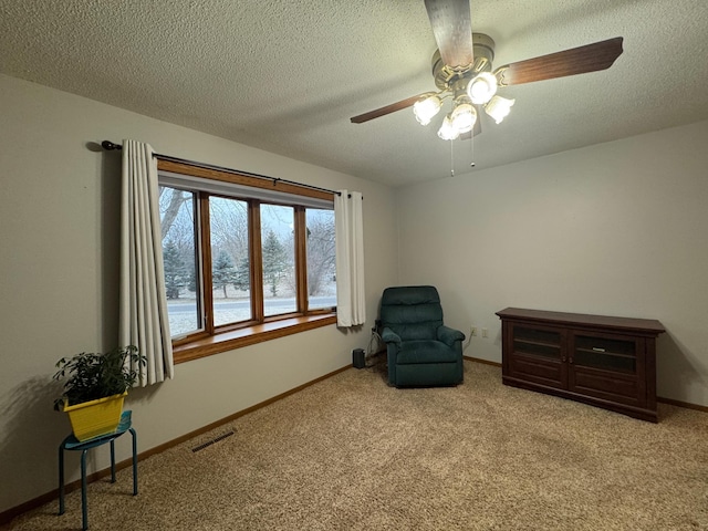 sitting room with ceiling fan, light colored carpet, and a textured ceiling