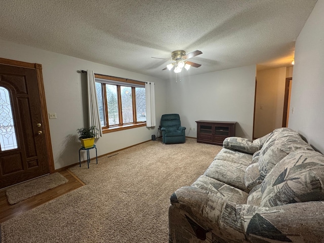 carpeted living room with ceiling fan and a textured ceiling