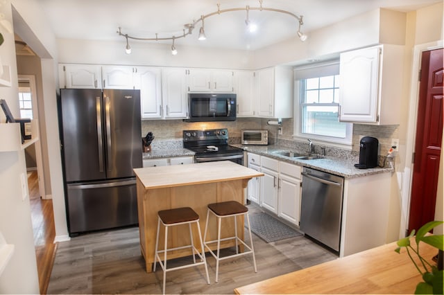 kitchen featuring sink, white cabinets, decorative backsplash, a center island, and stainless steel appliances